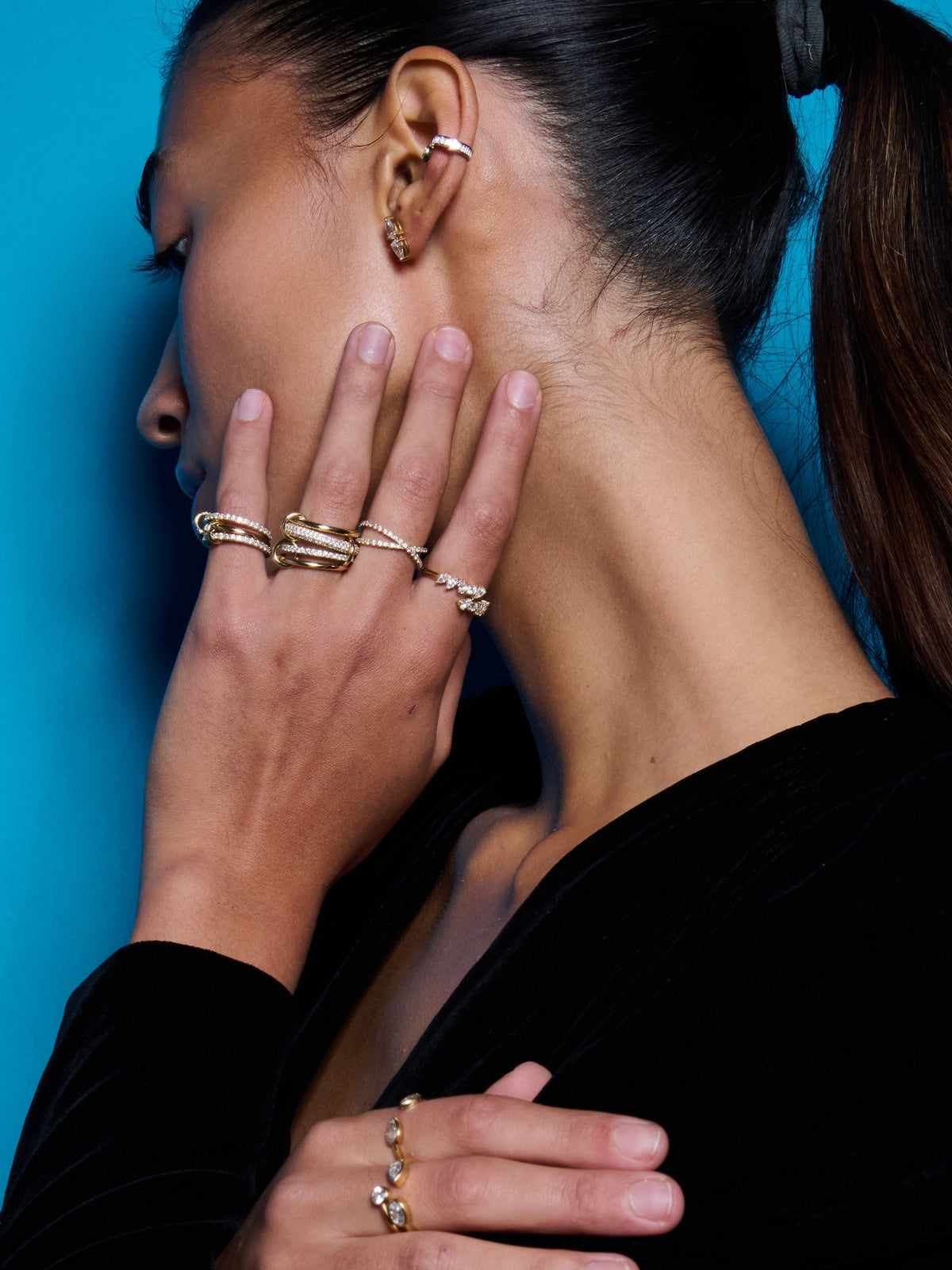 Model wearing ear cuffs and stacked rings against blue