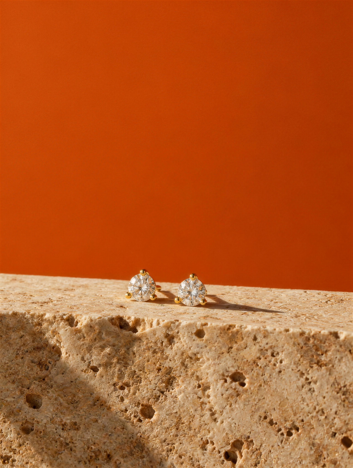 My First Diamond studs on travertine against burnt orange