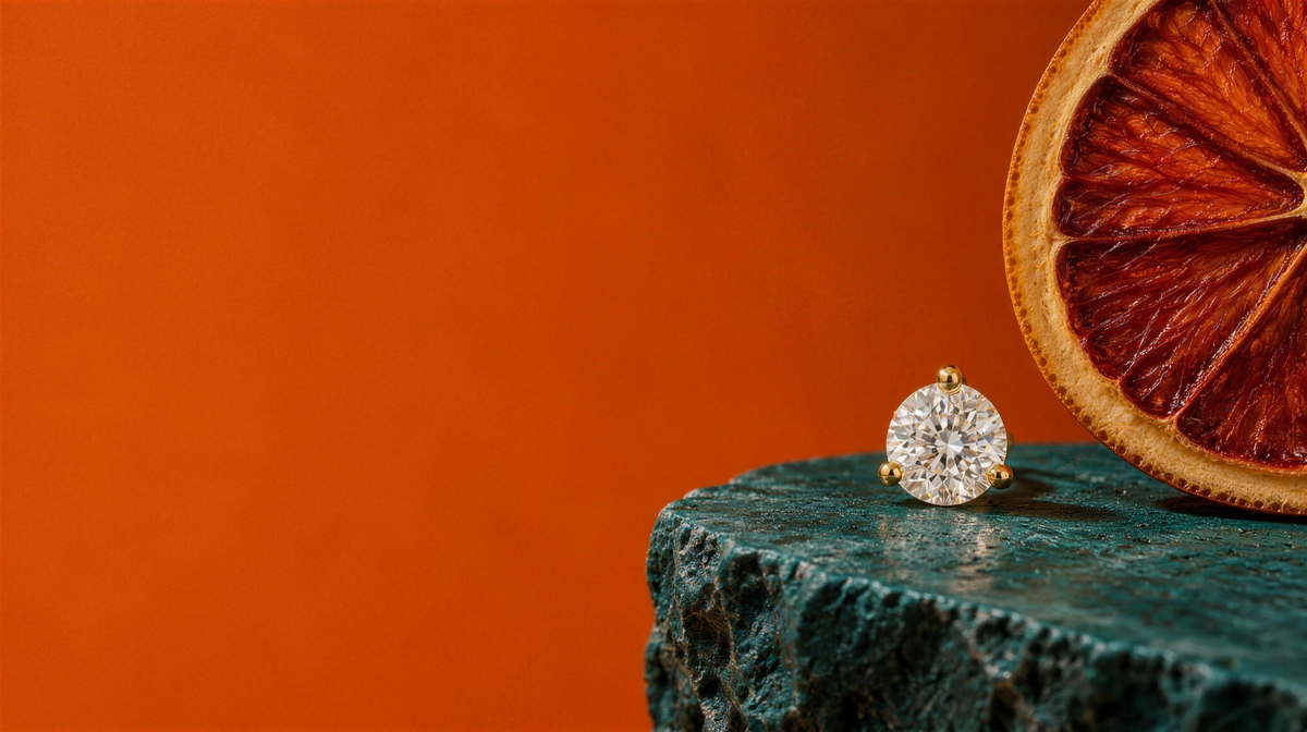 A single My First Diamond stud on teal stone with a dried orange slice